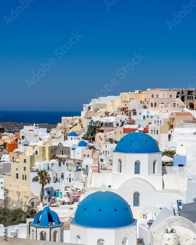 Cityscape of Oia town in Santorini island with old whitewashed houses and typical blue domes of orthodox churches, Greece. Greek landscape on a sunny day © mathilde