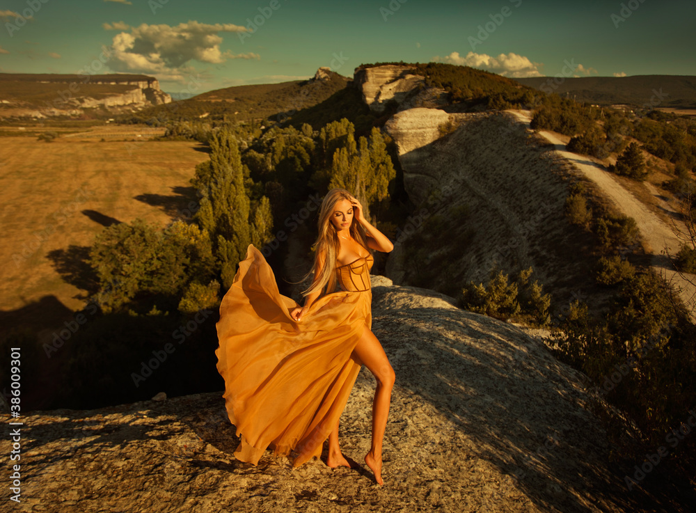 beautiful blonde in a beige dress on a cliff