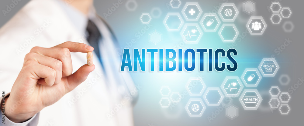 Close-up of a doctor giving you a pill with ANTIBIOTICS inscription, medical concept Close-up of a doctor giving you a pill with ANTIBIOTICS inscription, medical concept