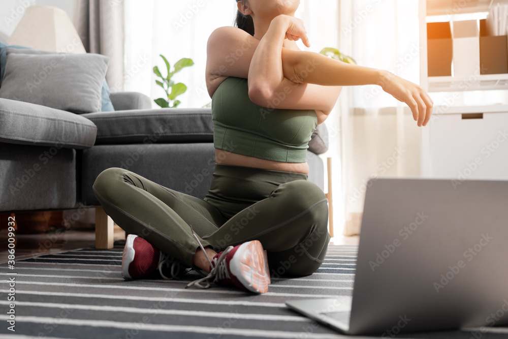 Close up fitness woman stretching her arm before exercise workout with laptop at home