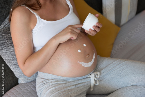 Pregnant woman applying cream