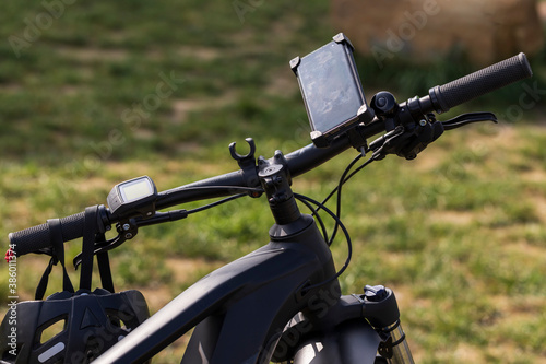 Electric bicycle handlebars. A navigation computer is attached to the handlebars and a bicycle helmet hangs on them.