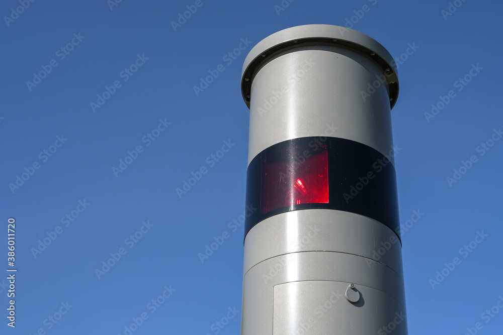 Part of a stationary speed limit enforcement with light radar, red flash and camera, traffic monitoring against dangerous speeding, blue sky, copy space Part of a stationary speed limit enforcement with light radar, red flash and camera, traffic monitoring against dangerous speeding, blue sky, copy space