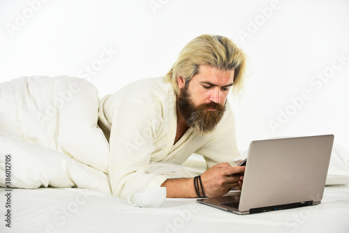 Social networks dependence. Screen Time and Insomnia. Happy hipster drink coffee in bed. Bearded man enjoy coffee and surfing internet laptop. Morning coffee routine. Social media. Modern life