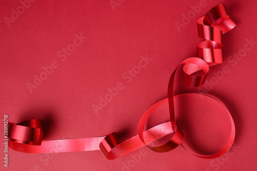 Red ribbon for presents or surprises for Christmas, new year, Valentine's day, international women's day or for celebrating holidays on a red background wity copy space. photo