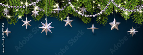 Green spruce branches with silver beaded garland and shiny stars.