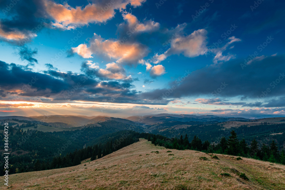 Sunset over the autumn forests in the Carpathian mountains, last sunrays painting the horizon.