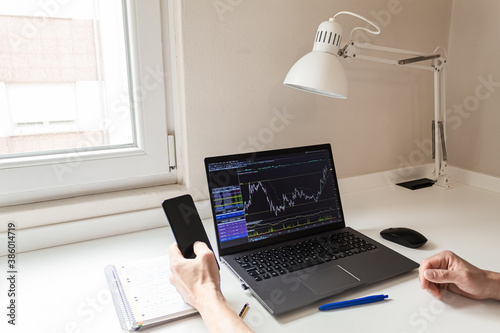 arms of a businessman while working from home with his laptop and mobile phone