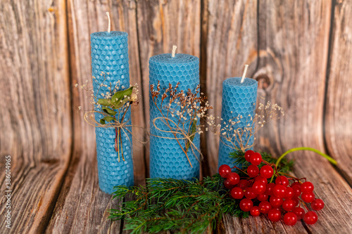 Blue honey candles handmade from natural wax on a background of wooden boards. Elements from natural materials. Christmas or New Year's composition. Photo for postcards.