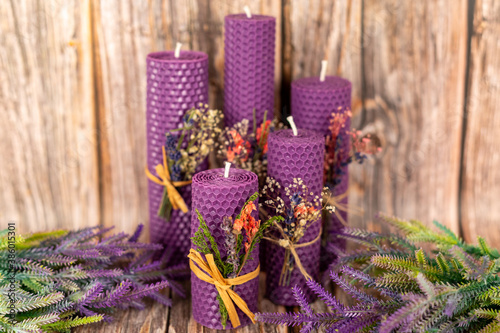 Purple honey candles handmade from natural wax on a background of wooden boards. Elements from natural materials. Christmas or New Year s composition. Photo for postcards.