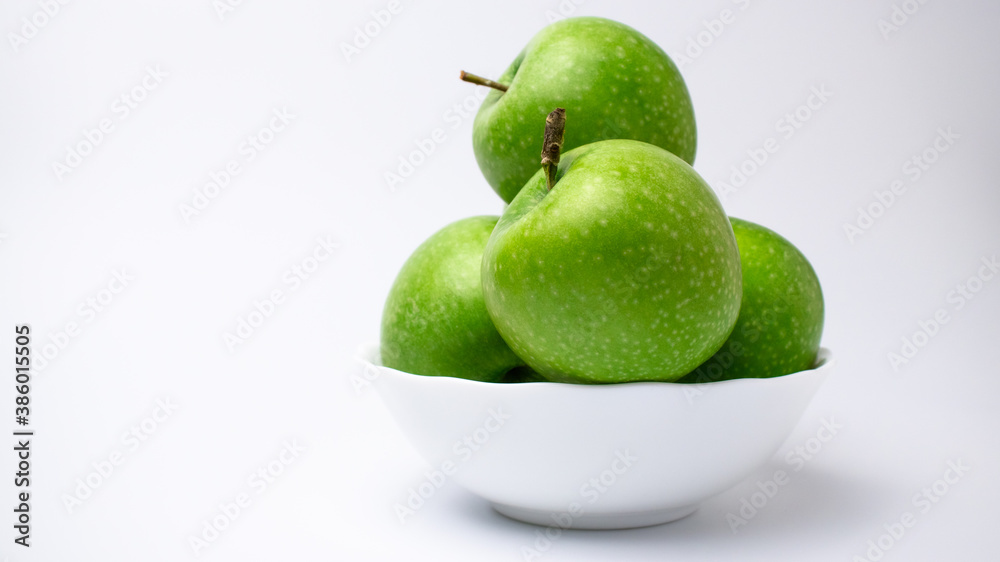 Green apples in white plate on plain backdrop, isolated. Green apples in white plate on plain backdrop, isolated.
