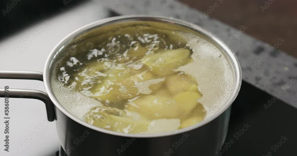Handheld shot of potato wedges boiling in saucepan Handheld shot of potato wedges boiling in saucepan