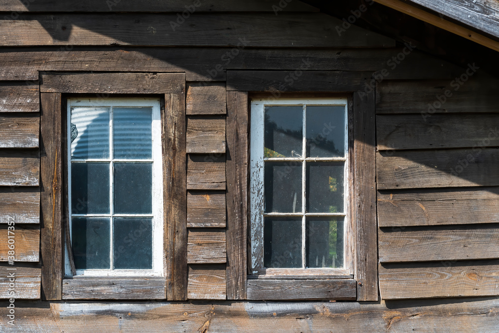 Couple of old wooden windows on a wooden facade