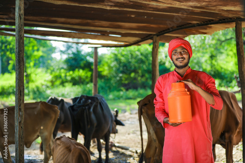 Indian farmer holding milk bottle in hand at dairy farm