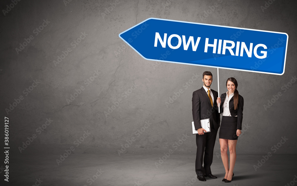 Obraz premium Young business person in casual holding road sign with NOW HIRING inscription, new business direction concept