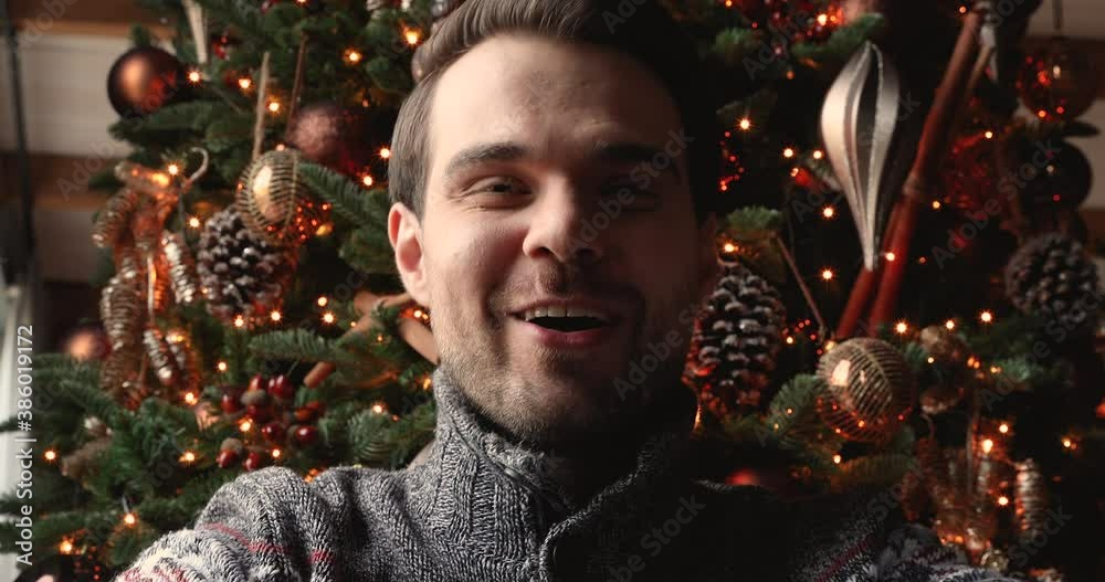 Close up web cam view portrait positive guy sit near decorated glowing festive fir tree enjoy videocall talk on winter holidays, congratulate relatives Merry Christmas. Video call remote chat concept Close up web cam view portrait positive guy sit near decorated glowing festive fir tree enjoy videocall talk on winter holidays, congratulate relatives Merry Christmas. Video call remote chat concept