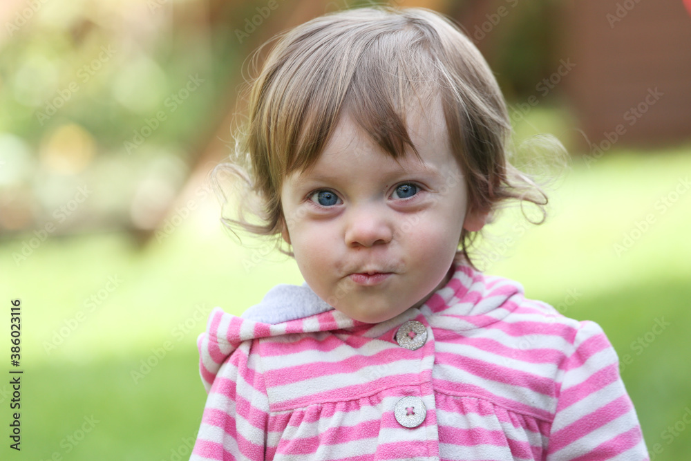 Close Up Portrait of a little 18 Month Old Girl with Big Blue Eyes and Curly Hair, a girl Playing Outside, Funny Face Expression, Happy baby Close Up Portrait of a little 18 Month Old Girl with Big Blue Eyes and Curly Hair, a girl Playing Outside, Funny Face Expression, Happy baby