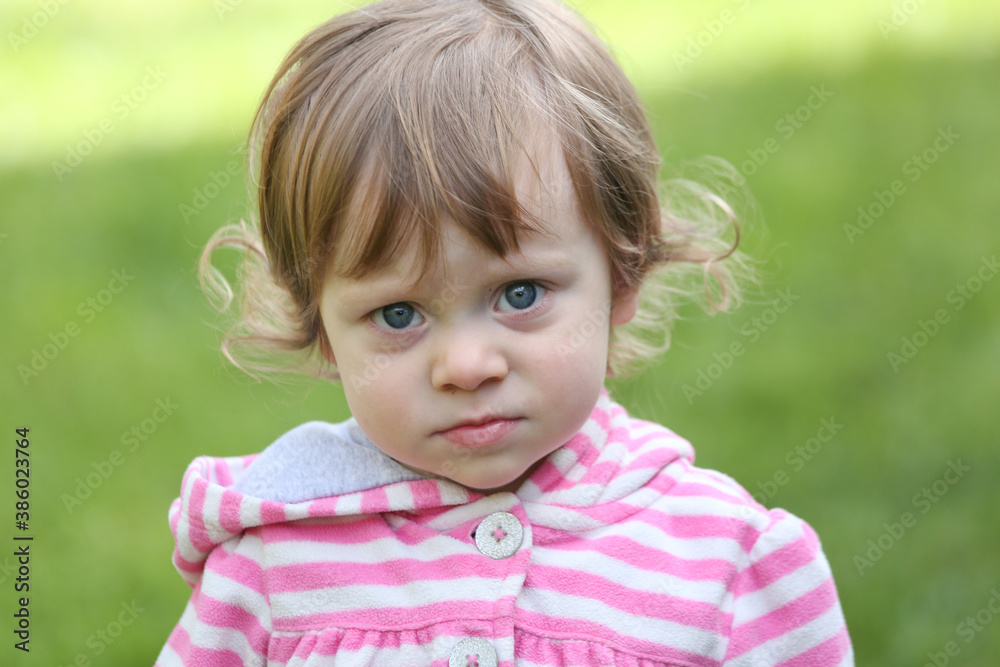 Close Up Portrait of a little 18 Month Old Girl with Big Blue Eyes and Curly Hair, a girl Playing Outside, Funny Face Expression, Happy baby Close Up Portrait of a little 18 Month Old Girl with Big Blue Eyes and Curly Hair, a girl Playing Outside, Funny Face Expression, Happy baby