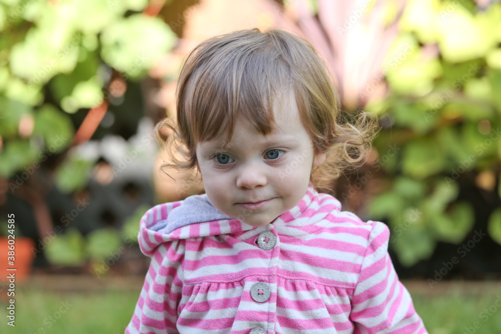 Close Up Portrait of a little 18 Month Old Girl with Big Blue Eyes and Curly Hair, a girl Playing Outside, Funny Face Expression, Happy baby Close Up Portrait of a little 18 Month Old Girl with Big Blue Eyes and Curly Hair, a girl Playing Outside, Funny Face Expression, Happy baby