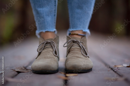 Brown boots with laces of a traveler on the feet of a woman close-up on a wooden bridge on an autumn day