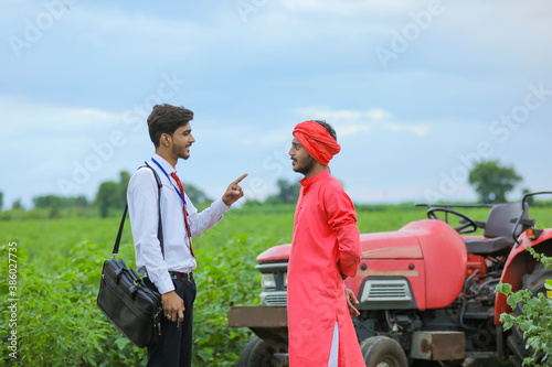 Young indian farmer and bank officer with new tractor at agriculture field