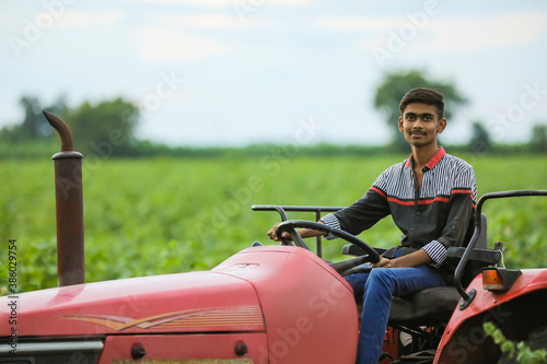 Young indian with tractor at agriculture field