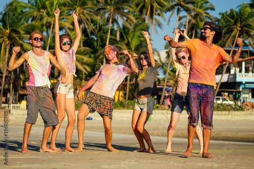 happy people in colorful holi paint play on beach on festive in Goa beach India © yurakrasil