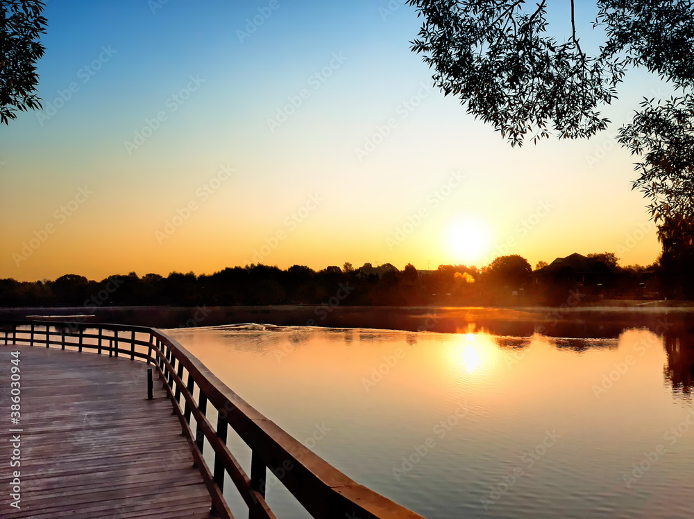 Obraz premium mellow sunrise sky and countryside landscape with rural scenery reflection in pond water. Natural color of summer morning. Sunset in park. Nature background