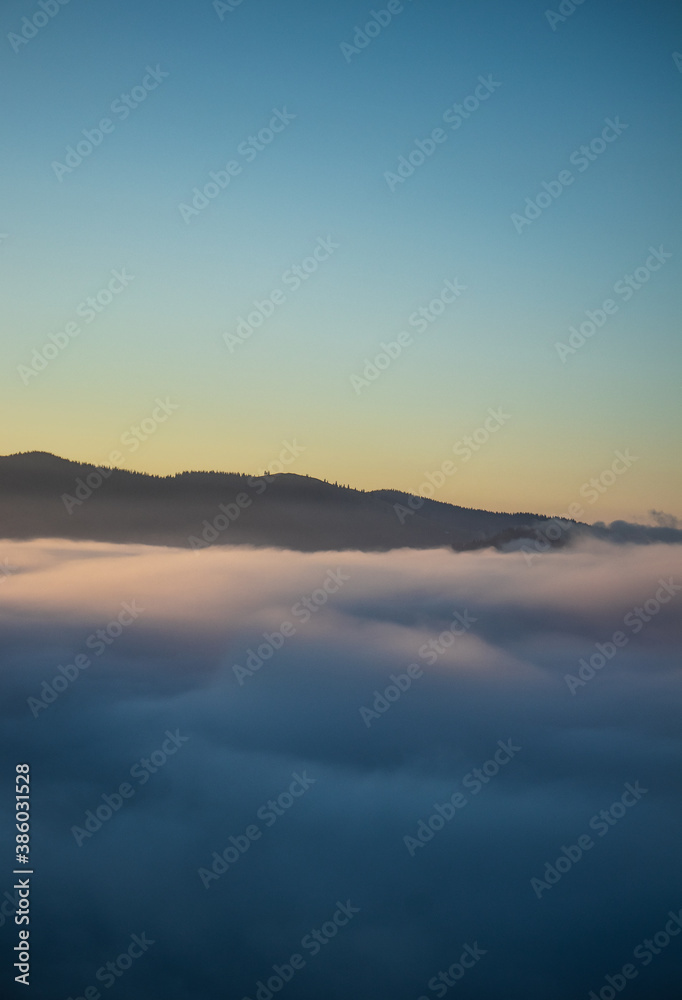 Over the clouds view, mountains in the background, sunrise
