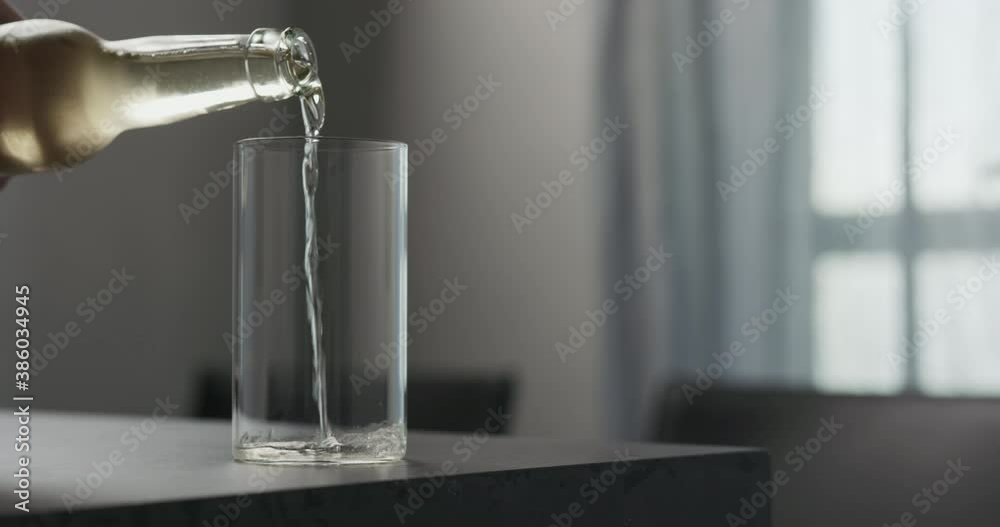 Slow motion man pour soda drink from a bottle into highball glass on concrete countertop with copy space Slow motion man pour soda drink from a bottle into highball glass on concrete countertop with copy space