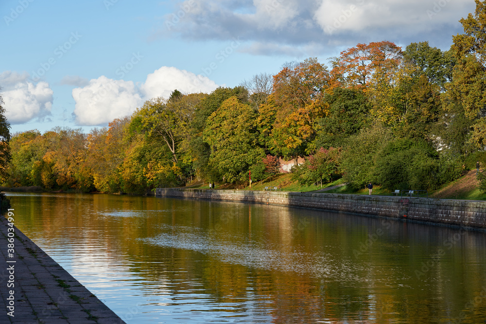 Fototapeta premium Riverside of Aura river in autumn colors with blue sky on the background. Copy space.