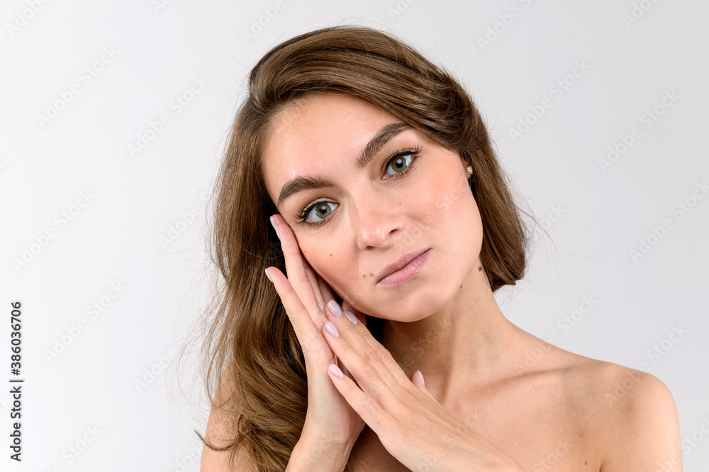 Close up portrait of a beautiful woman on white background holding both hands near the cheek Close up portrait of a beautiful woman on white background holding both hands near the cheek