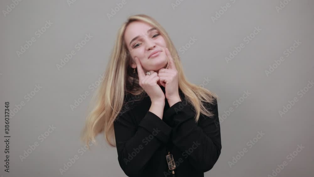 Hold arms hands cheeks cheekbones overjoyed palms touch chin charming smile. Young attractive woman, dressed black sweater with green eyes, blonde hair, background Hold arms hands cheeks cheekbones overjoyed palms touch chin charming smile. Young attractive woman, dressed black sweater with green eyes, blonde hair, background