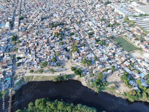 Vista aérea desde un dron, de una zona de casas de personas pobres, que viven frente a un río contaminado.