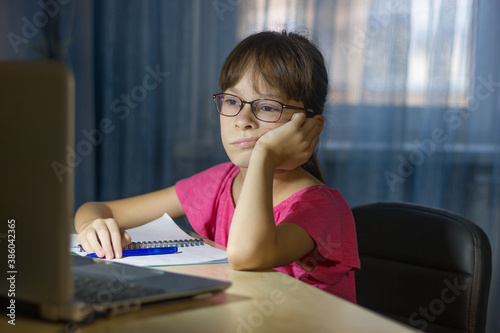 Tired child in front of the computer. Online education for kids. Tired and bored teenage girl is studing.