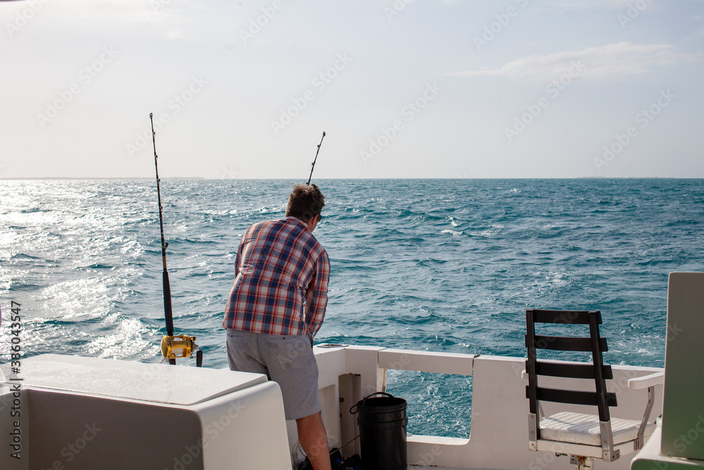 Fototapeta premium A man checks his fishing rods on a charter boat in Varadero, Cuba on a day excursion deep sea fishing in the Caribbean Ocean