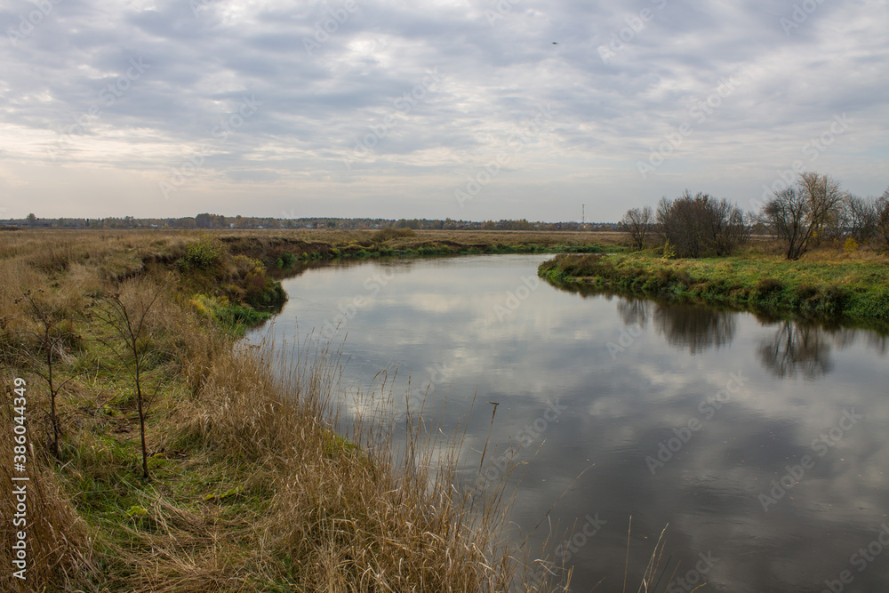 Autumn landscape - bend of the river with yellow grass and reflection of the cloudy sky and space for copying Autumn landscape - bend of the river with yellow grass and reflection of the cloudy sky and space for copying