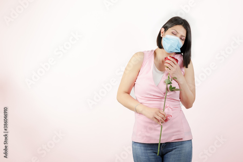 woman wearing mask in studio handling a red rose
