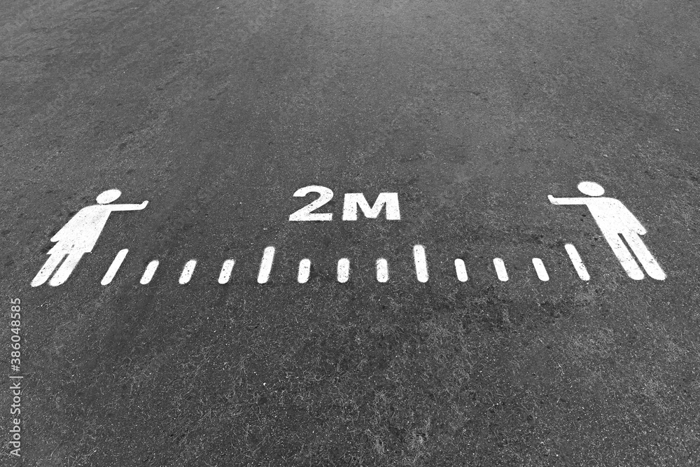 Fototapeta premium White painted 2 meters social distance sign on an asphalt road, pavement