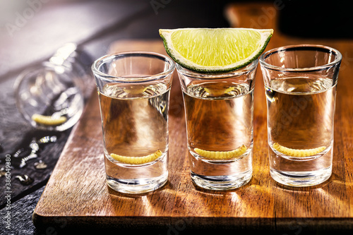 several glass of mezcal (or mezcal), typical and exotic brandy from mexico, with larva in the background and lemon photo