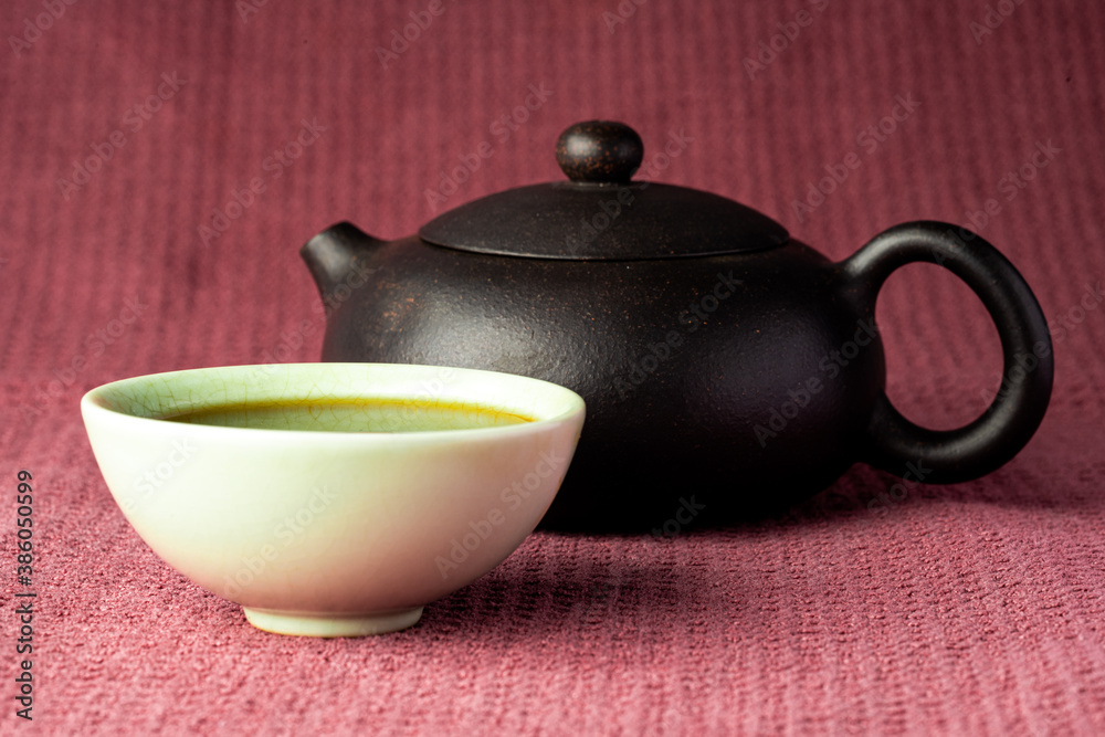 Chinese tea steaming in a small green teacup isolated with a black background and red surface Chinese tea steaming in a small green teacup isolated with a black background and red surface