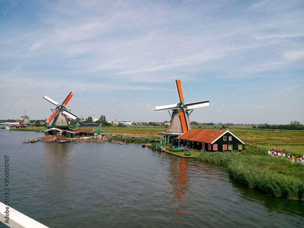 Fototapeta premium windmill, holland, mill, dutch, netherlands, water, landscape, wind, sky, old, architecture, blue, traditional, rural, river, kinderdijk, nature, green, village, europe, windmills, energy, farm, landm