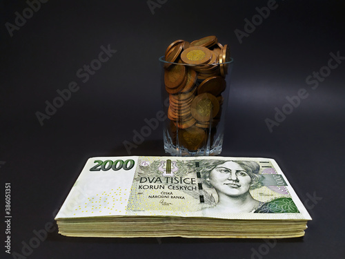 Close-up on Czech banknotes stacked next to each other next to a glass full of Czech 50 crowns on a dark background photo