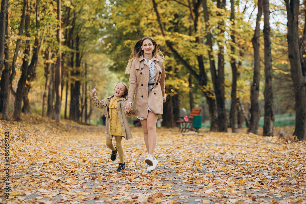 Fototapeta premium Happy mother and her beautiful daughter have fun and walk in the autumn park.