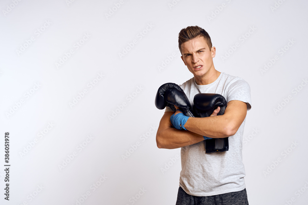 Strong man with boxing gloves and in a white t-shirt on an isolated background cropped view of the model