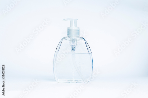 Transparent dispenser bottle for antiseptic or cosmetics with black button cap on light gray background.Coronavirus protection concept.