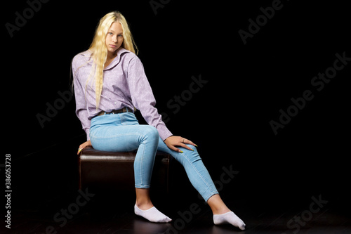 Cute Smiling Blonde Girl Sitting on High Chair in Studio