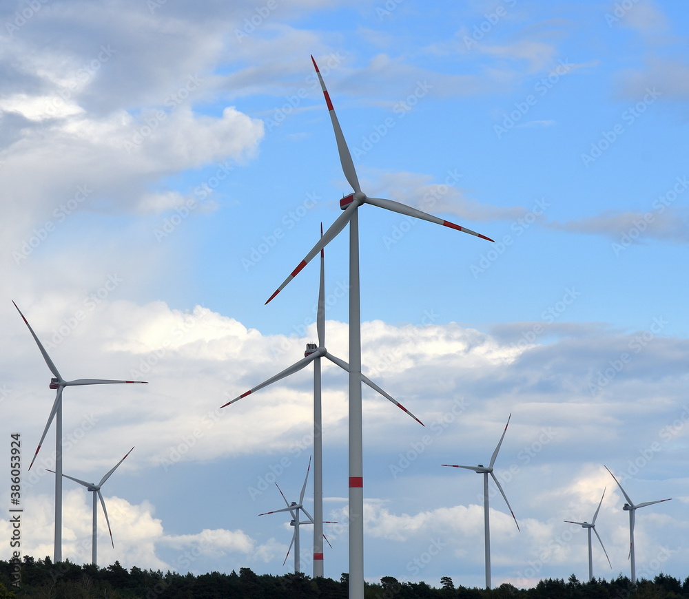 Windpark mit dreiblättrigen Windrädern vor blauem Himmel mit weißen Wolken Windpark mit dreiblättrigen Windrädern vor blauem Himmel mit weißen Wolken