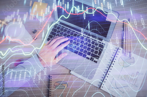 Double exposure of man's hands typing over computer keyboard and forex graph hologram drawing. Top view. Financial markets concept.