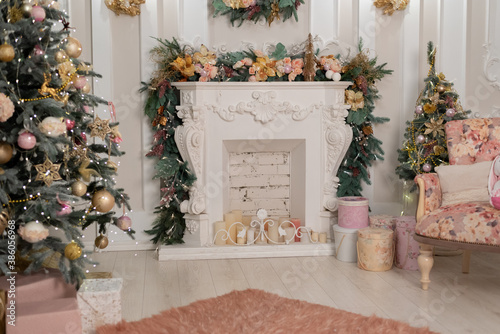 beautifully decorated bright room for the holiday season. Christmas tree in pink colors, gifts are under the Christmas tree. the fireplace is decorated with garlands 